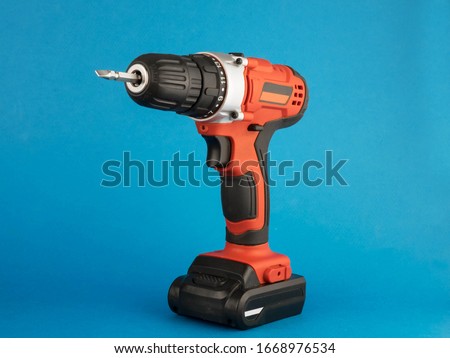 red electric drill with a nozzle on a blue background