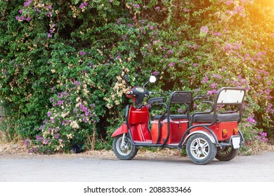 Red Electric Rickshaw Or E-rickshaw Commercial Vehicle Display With Selective Focus Under Daylight At Kemer, Turkey. Rent Transport For Tourists.