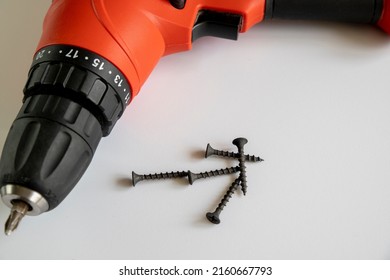 Red Electric Screwdriver Or Drill With Screws Isolated On  White Background. 