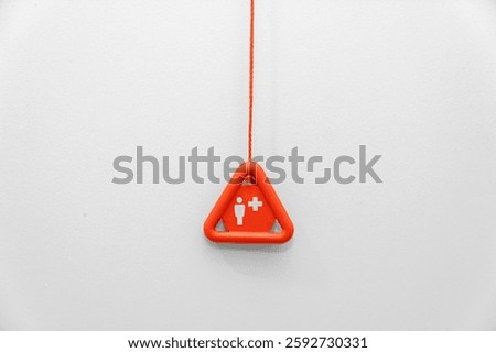 Red emergency button with handrail on wall in the disabled toilet. Security and assistance for disabled, senior concept. Emergency button in a special toilet for pregnant woman, elder and disabled.
