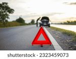 red emergency stop sign with broken down car on the road waiting to be repaired. Close-up of red emergency stop sign placed on the road for vehicle accidents or breakdowns for road safety.