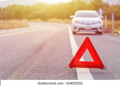 Red emergency stop sign and broken silver car on the road