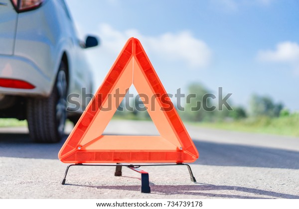 Red emergency stop sign and broken white SUV car\
on the road.red warning triangle on asphalt road.Emergency stop\
concept.