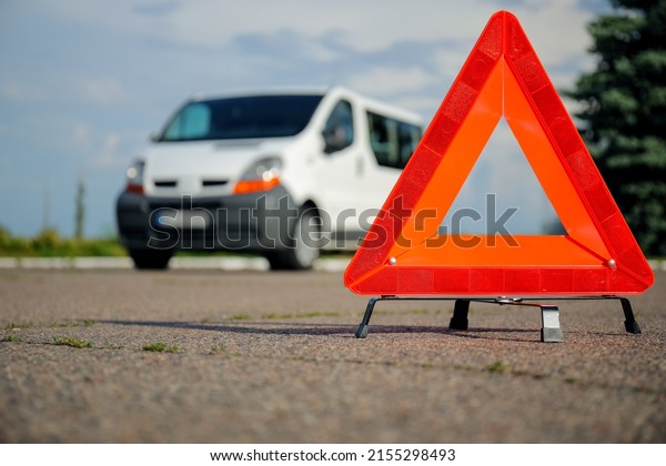 Red\
emergency triangle stop sign and broken car on\
road