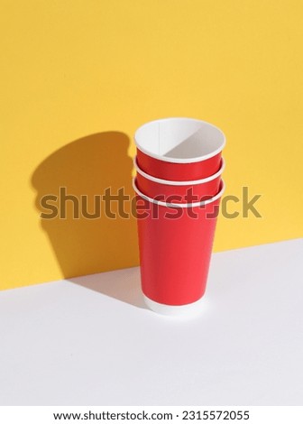 Red empty disposable cups on yellow-white background with shadow