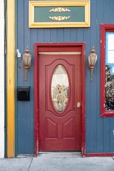 Red Entrance Door With A Round Window Of A House With A Wooden Facade. Mailbox At The Entrance