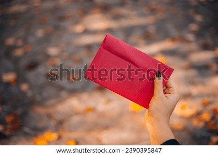 Red envelope in hand close up. Card mockup, blank flyer with, top view, flat lay. Blank invitation, holiday greeting card mockup with copy space.  