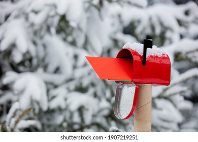 Red envelope in mailbox in a snow near pine tree in winter  - Powered by Shutterstock