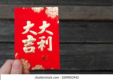 Red envelope packet chinese new year 2018, hongbao with the character 'good luck' in hand wooden background for Chinese New Year