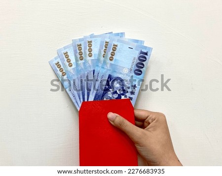 Red envelope and six thousand New Taiwan Dollars (6000 NTD). The concept of giving money, gifts, buying, lucky money and exchange.