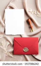 Red Envelope With Wax Seal And Blank Wedding Invitation Card Mockup On Satin Fabric. Flat Lay, Top View, Copy Space. Wedding Stationery Set.