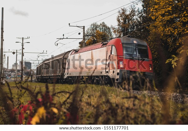 Red european style freight\
train with red locomotive is coming into a curve with closed box\
cars.