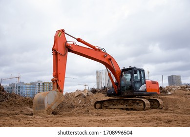 Red Excavator During Earthmoving At Construction Site. Backhoe Dig Ground For The Construction Of Foundation And Laying Sewer Pipes District Heating. Earth-moving Heavy Equipment On Road Works