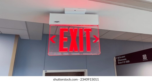 red exit sign above the door, a symbol of safety, escape, and a way out in emergencies. Represents hope and assurance in uncertain situations. Concept of finding an exit - Powered by Shutterstock