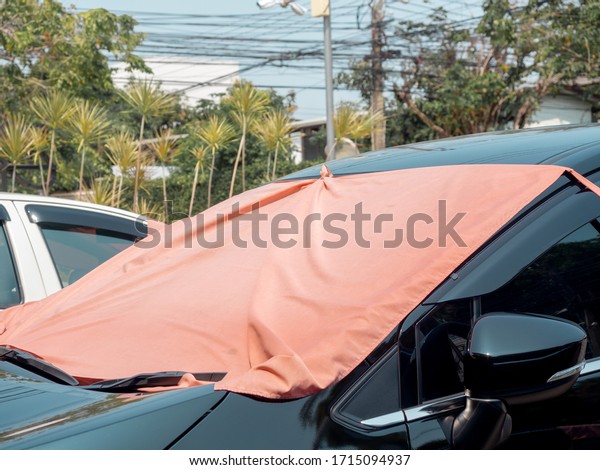 Red fabric covered on car front window for heat\
protection from sunshine. Car sunshade front windshield sunscreen\
simple style.