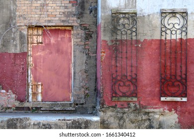 a red fadeing painted dirty warehouse in an alley with red door rusted and concrete steps - Powered by Shutterstock