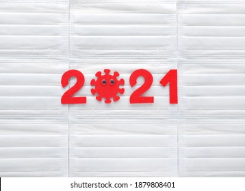 Red Felt Year Numbers 2021 On White Respirators Background. First Zero In The Form Of A Covid Virus With Googly Eyes. Results Of Vaccination Against COVID-19. Review Of The Coronavirus Year.