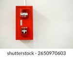 A red fire alarm and pull station mounted on a white wall, essential safety equipment for buildings. Highlights emergency preparedness and protection.