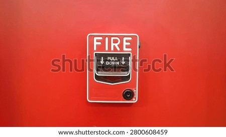 Red fire alarm pull station mounted on a red wall