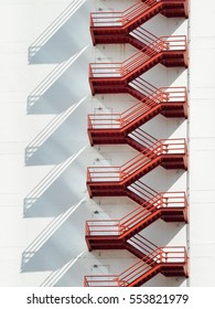 Red fire escape ladders on white building, Exterior view