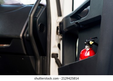 Red Fire Extinguisher In A Black Truck Door.