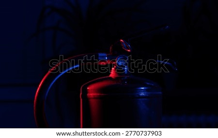 Red fire extinguisher illuminated with dramatic emergency lighting