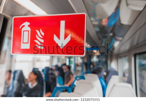 Red fire extinguisher sign sticker on the\
glass in the underground, train, subway or tube for safety in\
Europe, UK with a group\
passengers.