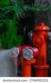 Red fire hydrant attached to curb with green foliage background.