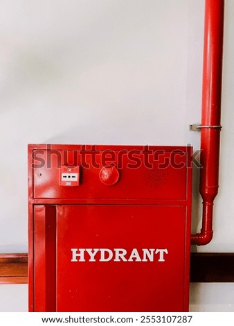 A red fire hydrant cabinet mounted on a white wall. The cabinet has a prominent 