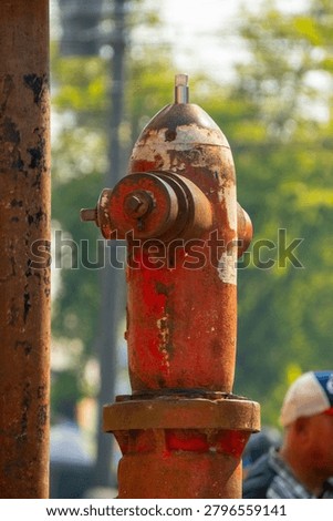 Red fire hydrant is a common sight on city streets. This hydrant shows significant signs of wear, with peeling paint and rust.