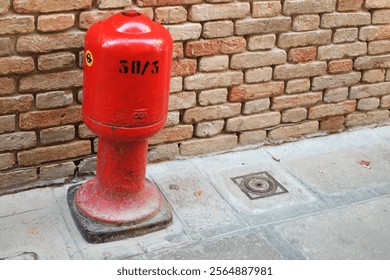 red fire hydrant in front of a red brick wall