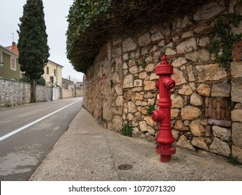 Red fire hydrant in front of a stone wall, Cres Croatia