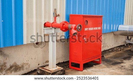 Red fire hydrant and hose box on the wall of a building.