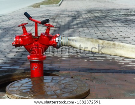 Red fire hydrant installed in the hatch, with an attached fire hose. 