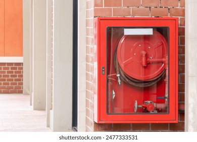 A red fire hydrant is mounted on a brick wall. The hydrant is red and has a clear glass case