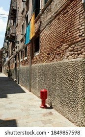 red fire hydrant next to a red brick and concrete wall on a canal in Venice