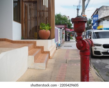 Red Fire Hydrant On City Street With Steps To Building And Car In Blurred Background 