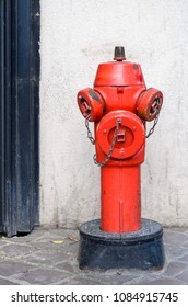 Red fire hydrant on a paved sidewalk to the side of a door frame for supplying water in times of a fire fighting emergency