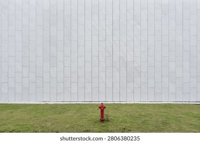 Red fire hydrant standing in front of a white marble tiled wall
