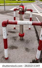 red fire hydrant surrounded by protective safety barriers near a road crossing.