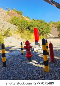 Red Fire Hydrant and Warning Post on Gravel Ground under Blue Sky