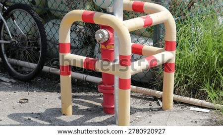 Red Fire Hydrant with Yellow and Red Striped Protective Bollard in Urban Setting