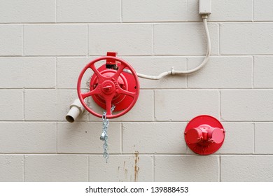 Red Fire Valve And Spout On A White Cinder Block Wall