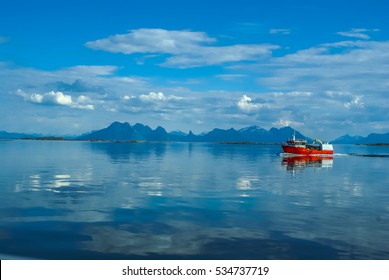 Red Fishing Boat Sailing On Water With Mountains In Distance Near Svolvaer In Norway.