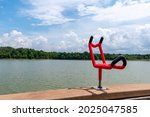A red fishing rod holder mounted to the dock on Freeman Lake in Elizabethtown, KY.  The lake has calm water and the sky is blue with cumulus clouds.