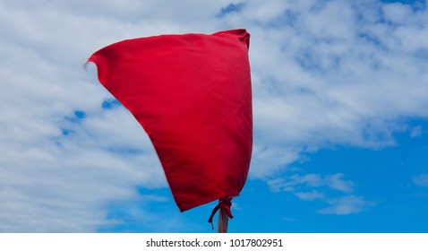 Red Flag Against A Sky With Clouds