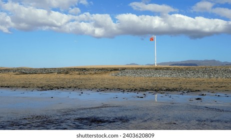 Red flag beach viewed from the ocean with sand dunes and cloudy sky in the background and large copy space. - Powered by Shutterstock