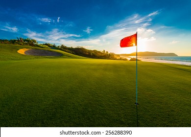 Red flag at the beautiful golf course at the ocean side at sunset, sunrise time.