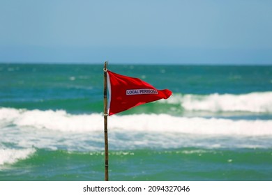 Red Flag Life Guard Danger Warning Sign On The Beach. No Swimming It's Forbidden Symbol, Dangerous Rip Tide Currents On Water, Enter At Your On Risk. Blue Sunny Sky And Turquoise Waves On Background