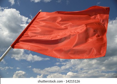 Red Flag On A Background Of The Dark Blue Sky With Clouds.